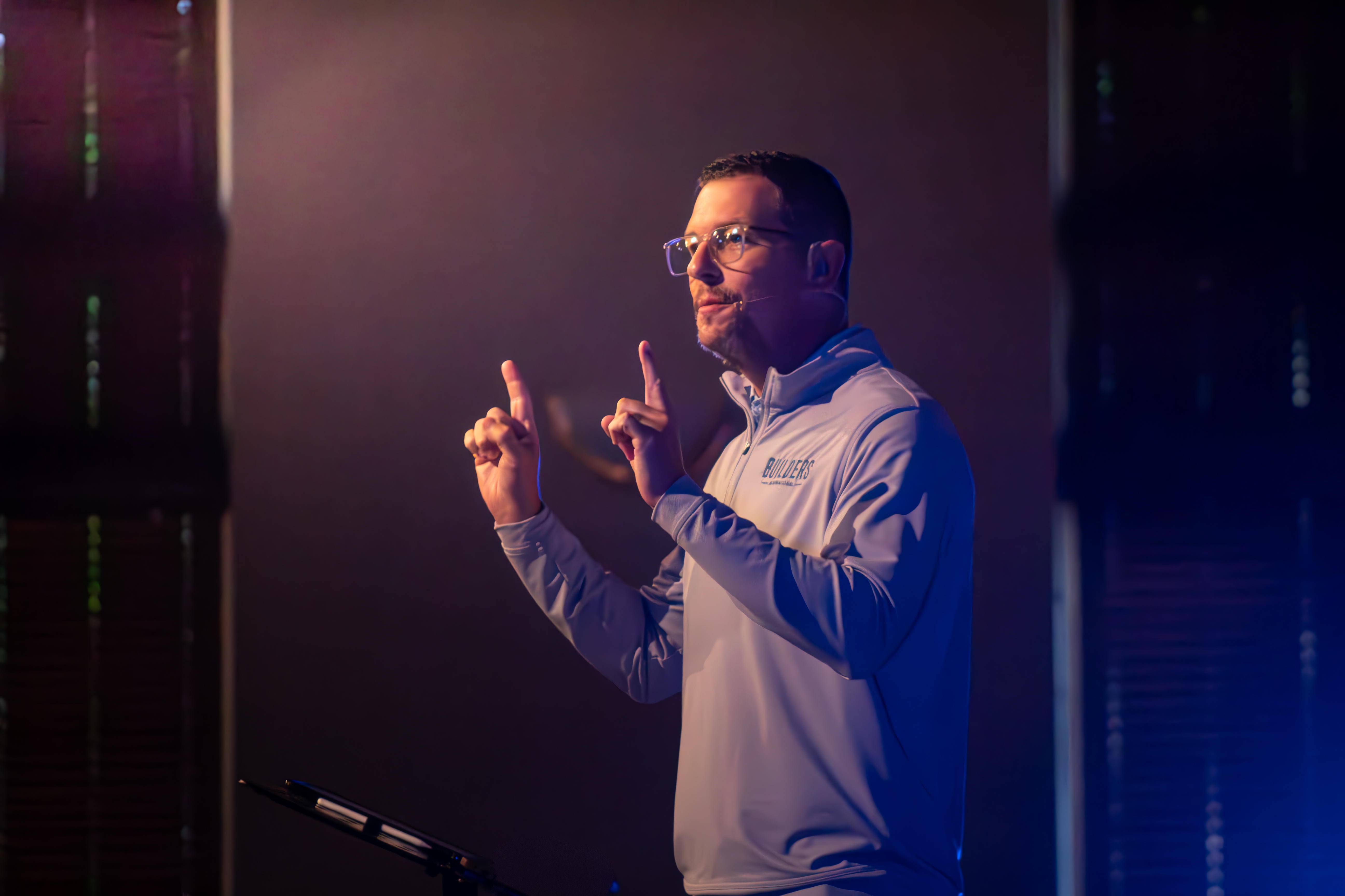 Jeremy Godwin speaking on stage with a headset microphone.